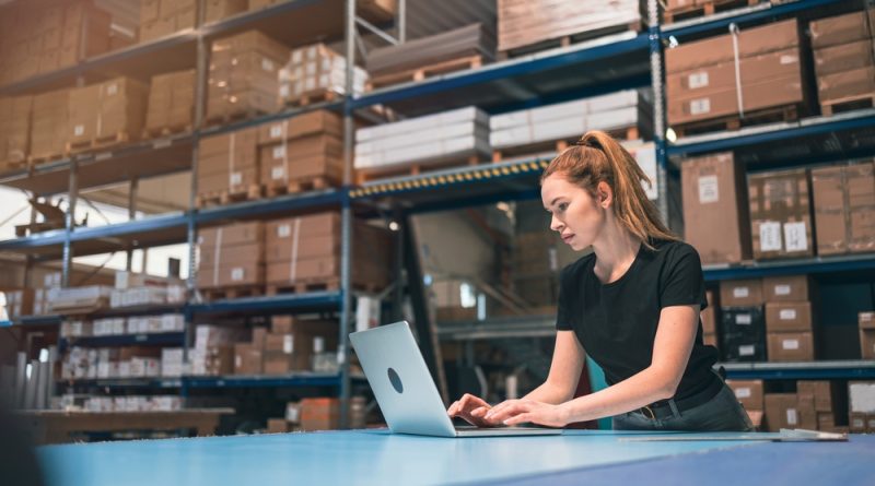 A lady working on her laptop in a warehouse