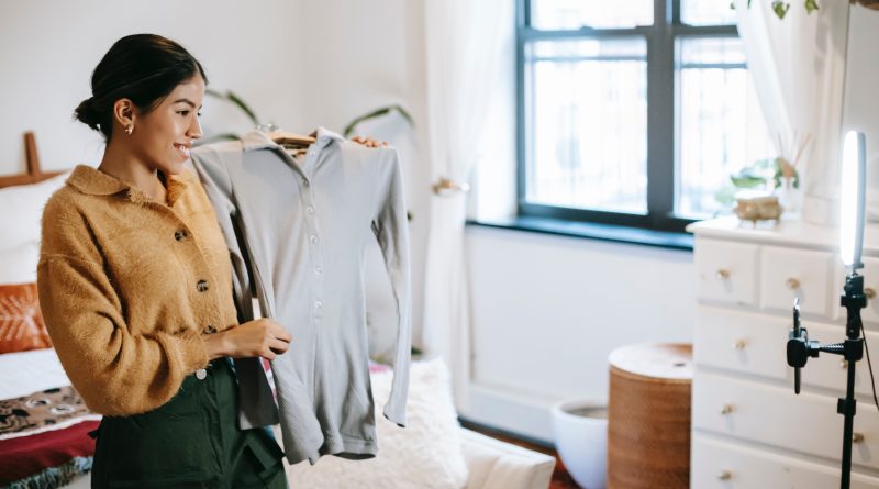 Influencer holding up a jumper in front of a camera