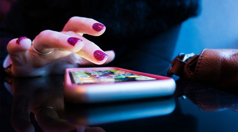 image of someone tapping on a bright phone screen to support retail mobile apps article