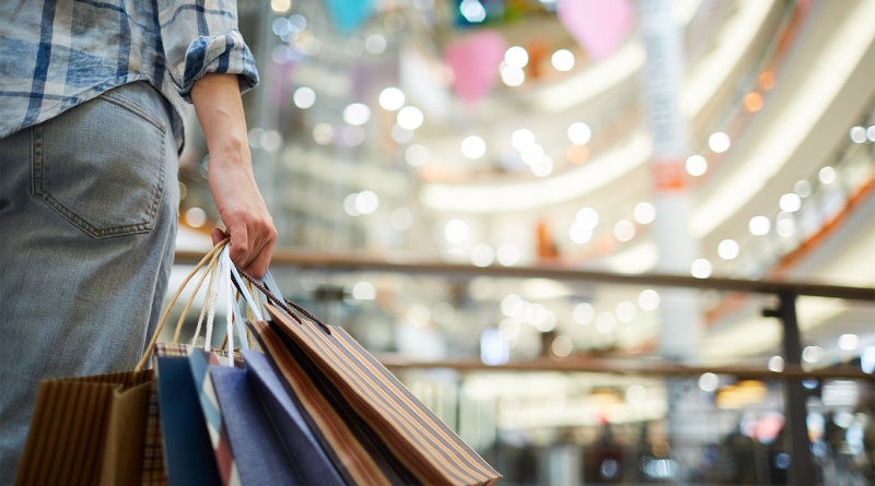 Person going up stairs in shopping mall with shopping bags to support article