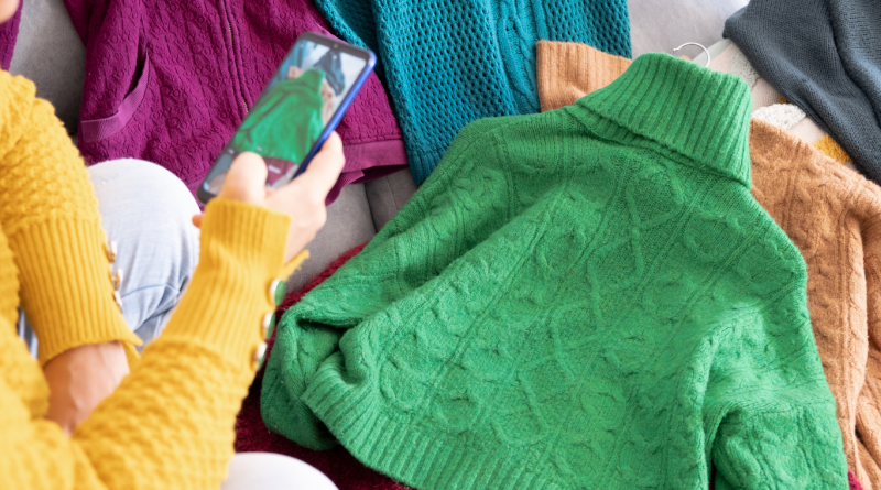 The Top 7 Best Online Thrift Stores to Shop in 2025 Person photographing colorful secondhand sweaters to sell online, representing the best online thrift stores for sustainable and affordable fashion.