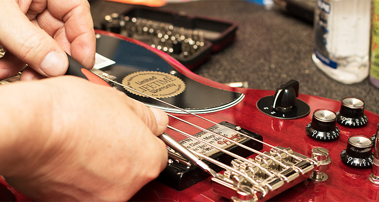 a person working on a Gibson EB-3 bass guitar.